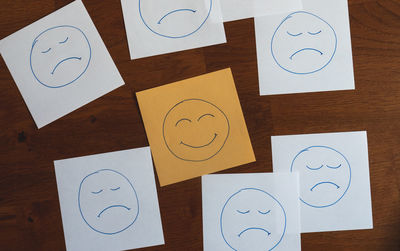 Close-up of text notes with happy face among sad faces