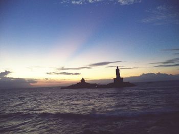 Silhouette lighthouse by sea against sky during sunset