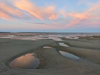 Scenic view of low tide against sky during sunset