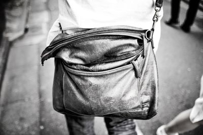 Midsection of man with shoulder bag standing on street