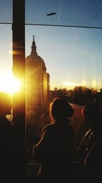 Silhouette woman in city against sky during sunset