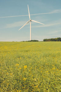 Wind turbines on field against sky