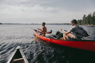 Men sitting in sea against sky