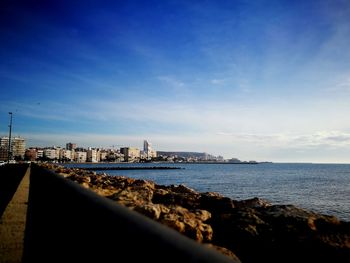 View of city at waterfront against cloudy sky