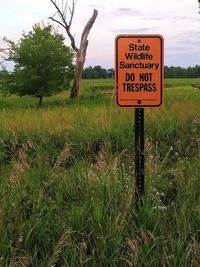 Information sign on field against sky