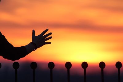 Silhouette hand against orange sky