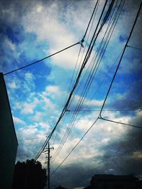 Low angle view of electricity pylon against cloudy sky