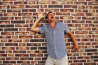 Man crying against brick wall
