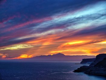 Scenic view of sea against dramatic sky during sunset
