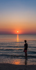 Man standing at beach during sunset