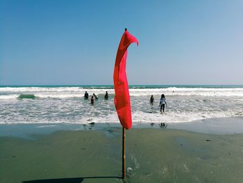 People on beach against clear sky