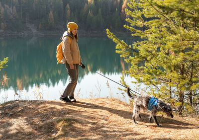 Rear view of man with dog standing in forest