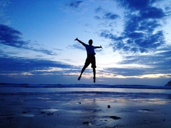 Silhouette of woman jumping in sea