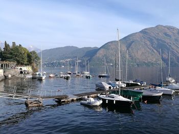 Sailboats moored on harbor by sea against sky