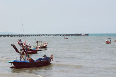 Fishing boats in sea against clear sky