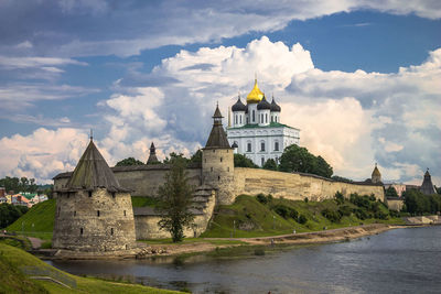 Buildings by river against sky