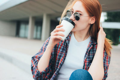 Young woman wearing sunglasses sitting outdoors