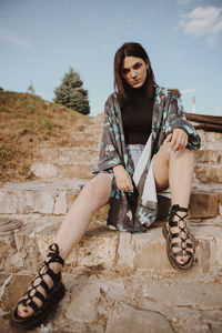 Full length portrait of fashionable woman sitting on steps