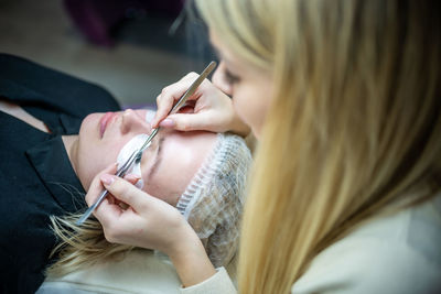 Midsection of woman applying eye patch to customer