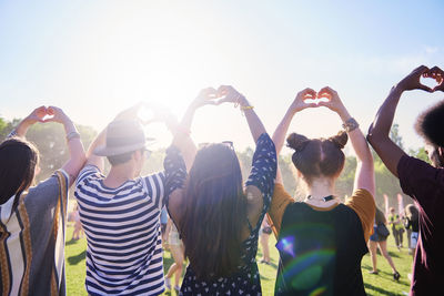 Rear view of friends making heart shape at music festival