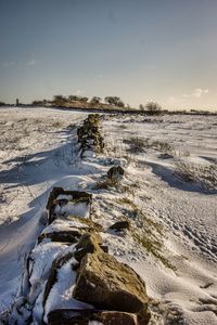 Rocks on snowy field against sky