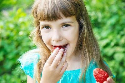 Smiling girl eating strawberry at farm