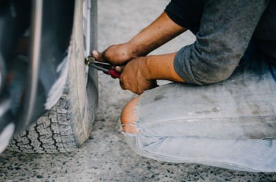 Low section of man holding camera while standing by car