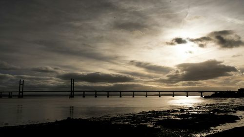 Bridge over river against cloudy sky