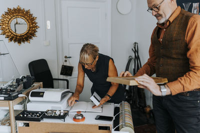 Elderly male entrepreneur examining picture frame by female colleague in antique shop