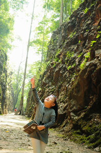 Woman on tree trunk amidst plants in forest