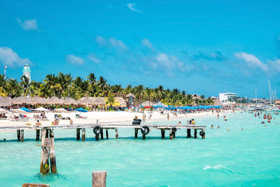 Tourists swimming or holidaying at beach, yachts or sailboats in the background