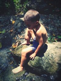 High angle view of boy sitting on rock