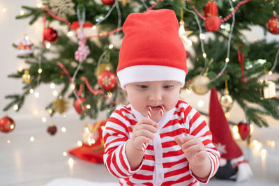 Cute baby eating candy cane at home