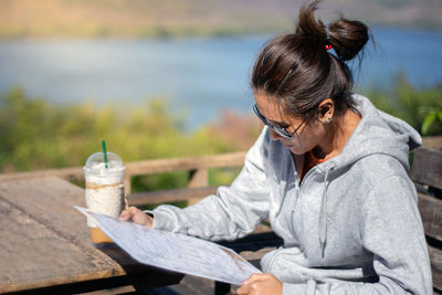 Woman reading menu while sitting on table at restaurant