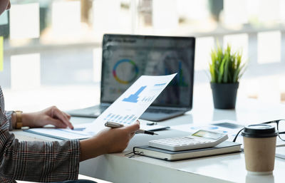 Midsection of businessman using laptop on table