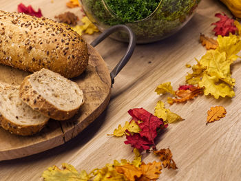 Autumn photocomposition of cereal bread with fresh thyme and dried leaves