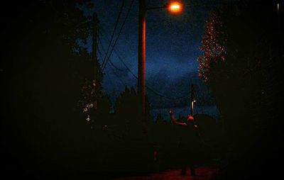 Illuminated street light against sky at night