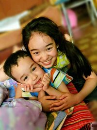 Portrait of smiling siblings lying on floor at home