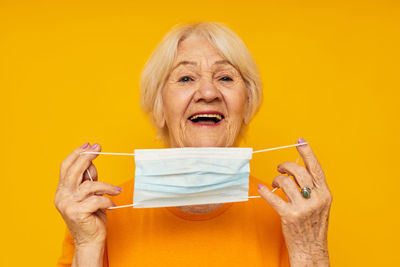 Close-up of woman holding gift against yellow background