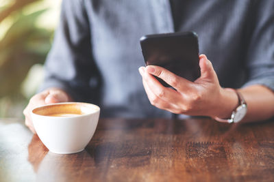 Midsection of woman using mobile phone at cafe