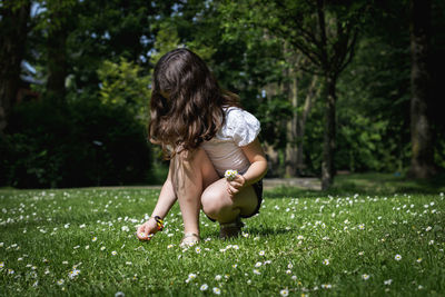 Rear view of woman sitting on field