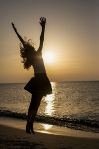 Silhouette woman at beach during sunset