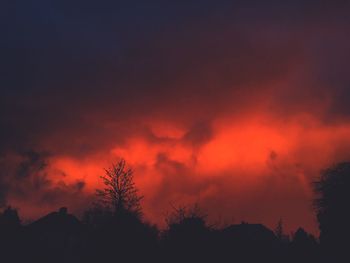 Low angle view of silhouette trees against dramatic sky