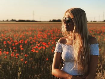 Woman wearing sunglasses on field against sky