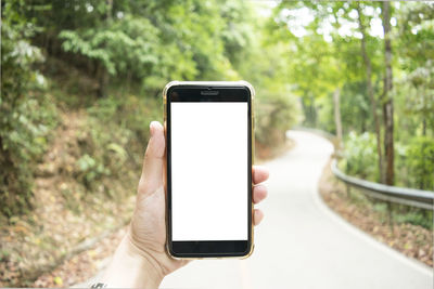 Close-up of human hand holding smart phone on road