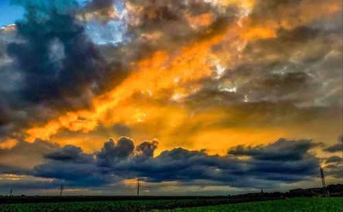 Scenic view of dramatic sky over field during sunset