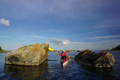 Woman on kayak against cloudy sky