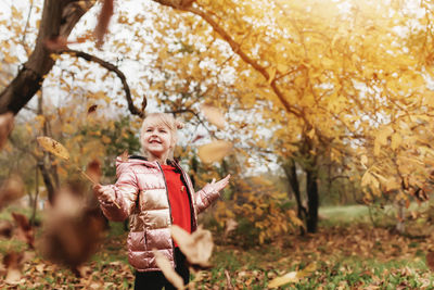 Full length of girl holding autumn tree