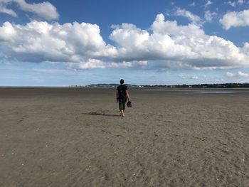 Rear view of woman on beach against sky