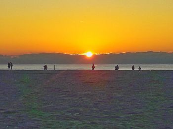 Silhouette people on beach against clear sky during sunset